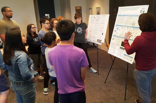 Students hearing from Prof. Berro about strategies on presenting a poster well.